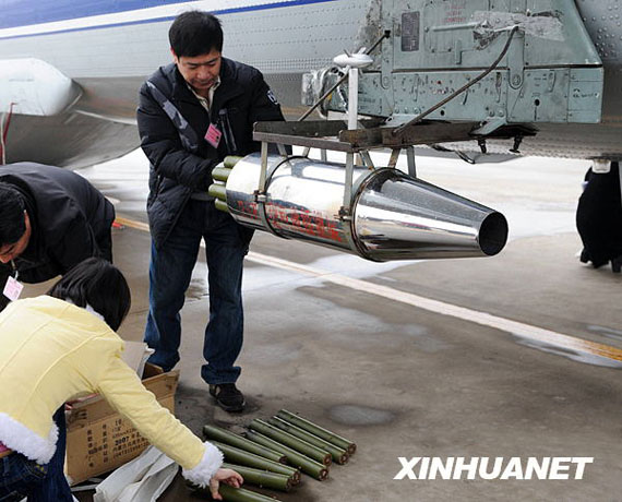 資料圖:2月8日,在河南省鄭州市新鄭機(jī)場,工作人員往飛機(jī)上裝掛人工增雨用的碘化銀催化劑。